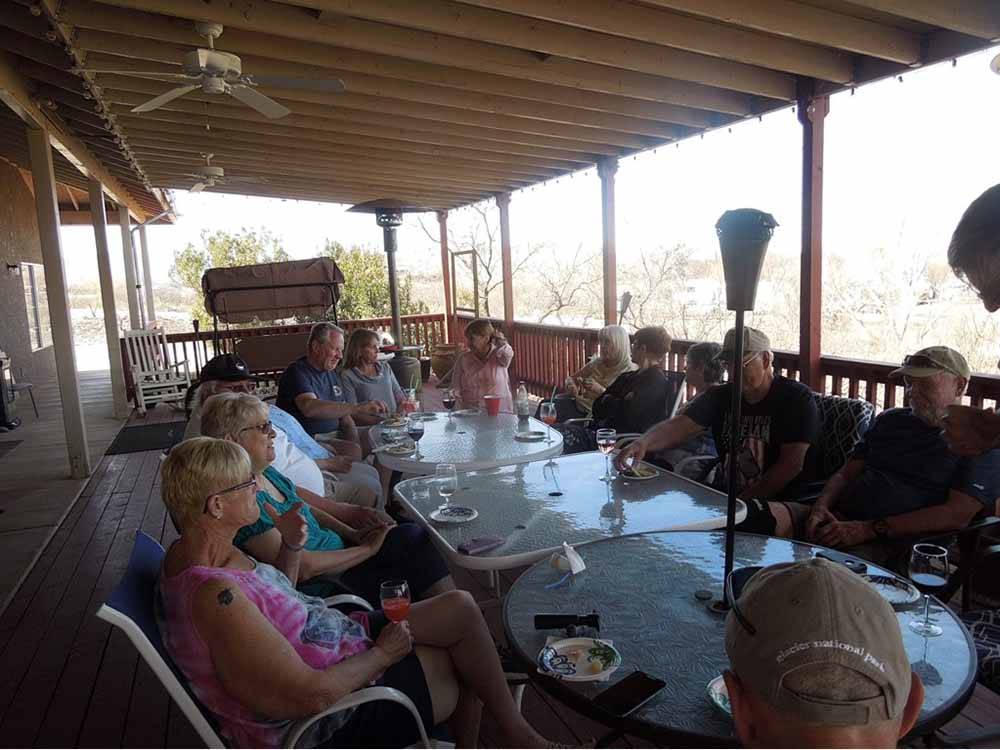 A group of people sitting at a long table outside at PATO BLANCO LAKES RV RESORT