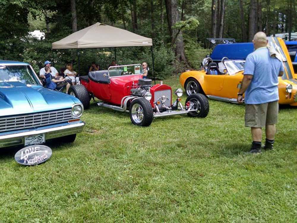 Man admiring brightly colored vintage muscle cars at car show at COZY ACRES CAMPGROUND/RV PARK