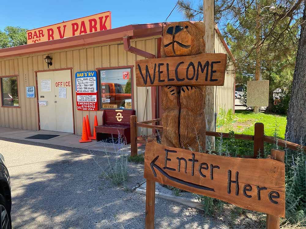 Wooden sign directing guest to main office at BAR S RV PARK