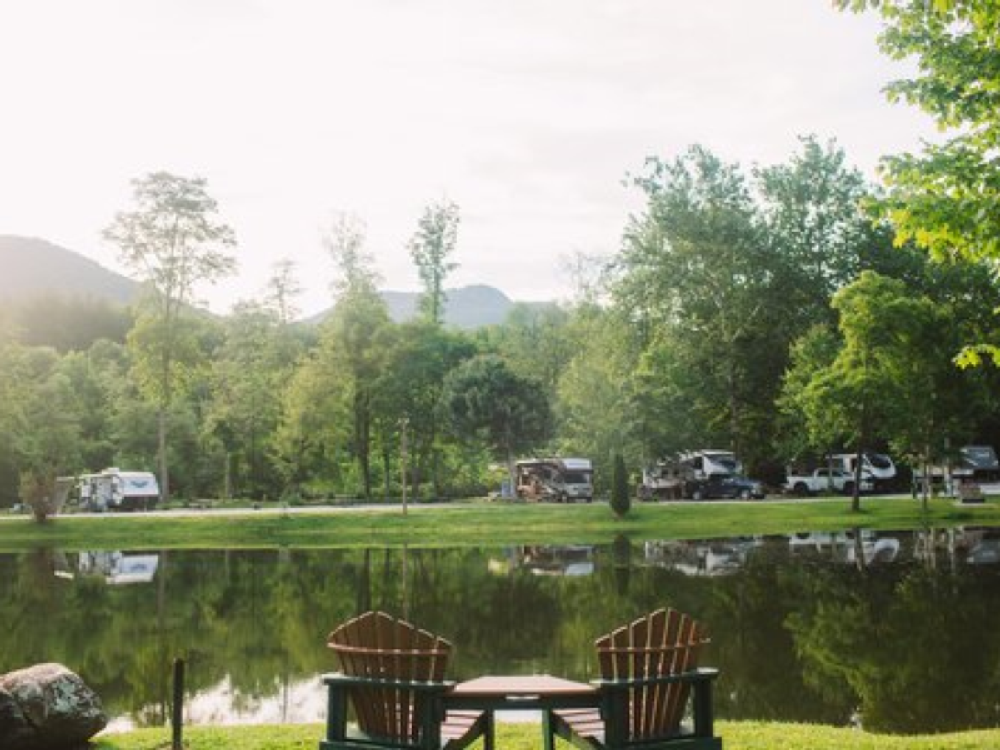 Adirondack chairs by the water at Mountain River Family Campground