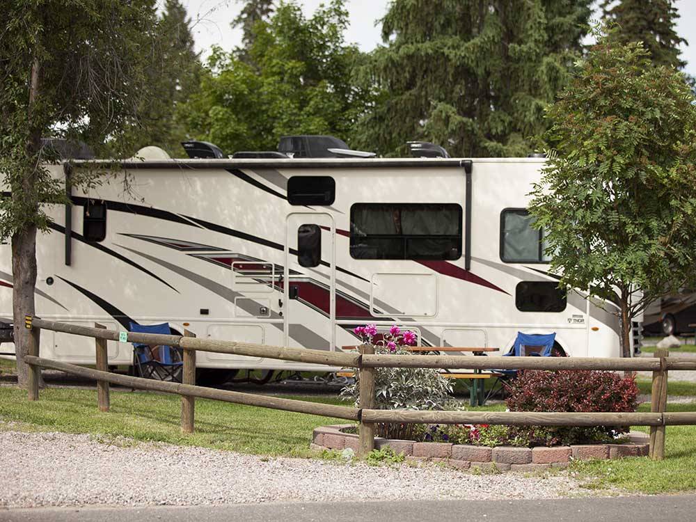 A motorhome parked in a site with chairs next to it at COLUMBIA FALLS RV PARK