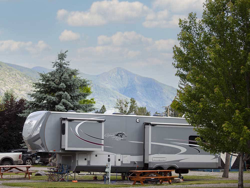 A fifth wheel in a gravel site next to a picnic bench at COLUMBIA FALLS RV PARK