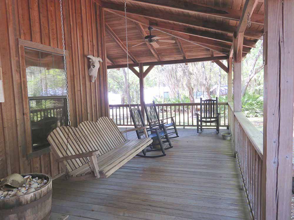 A swinging chair and rocking chairs on the deck at COUNTRY OAKS RV PARK & CAMPGROUND