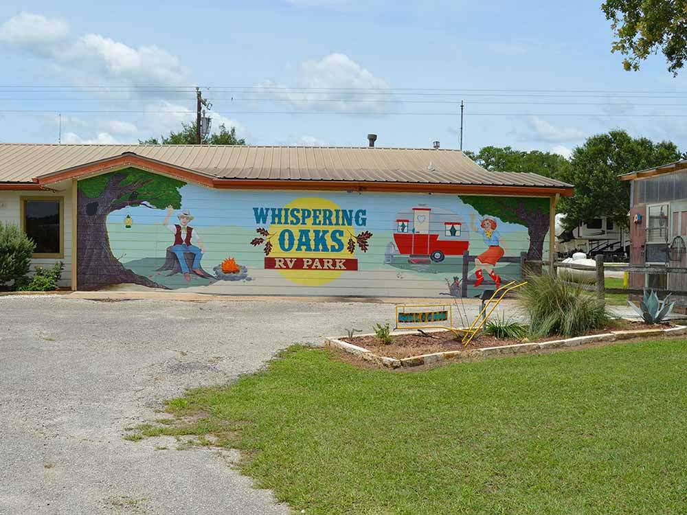 A building with the park name on it at WHISPERING OAKS RV PARK