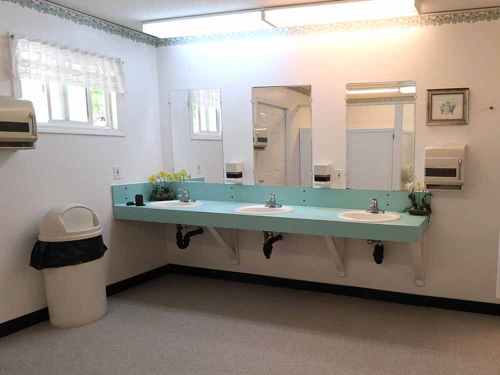 Bathroom with three sinks and stalls at PAIR-A-DICE RV PARK