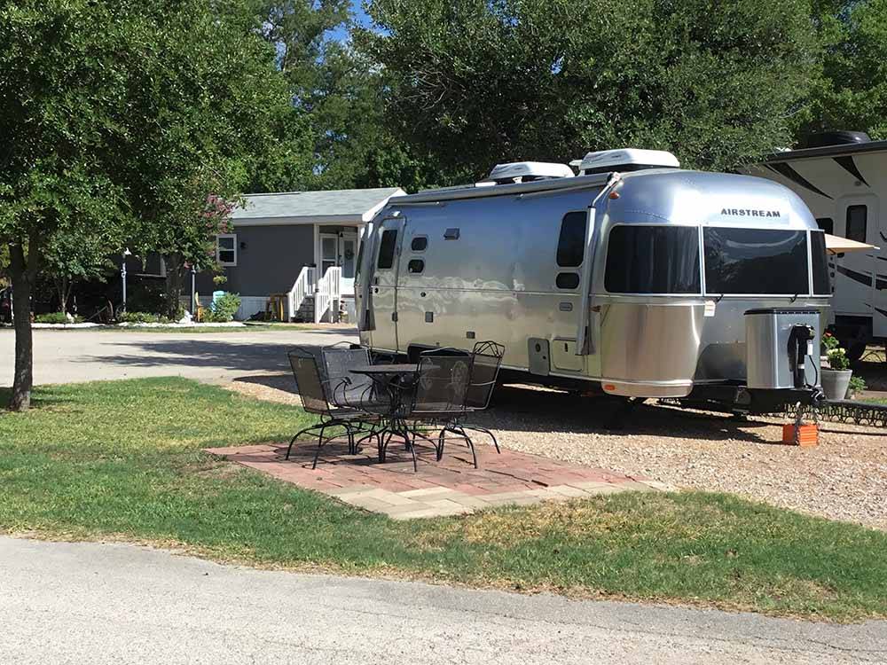 Airstream trailer parked near table and chairs at WOODLAND LAKES RV PARK