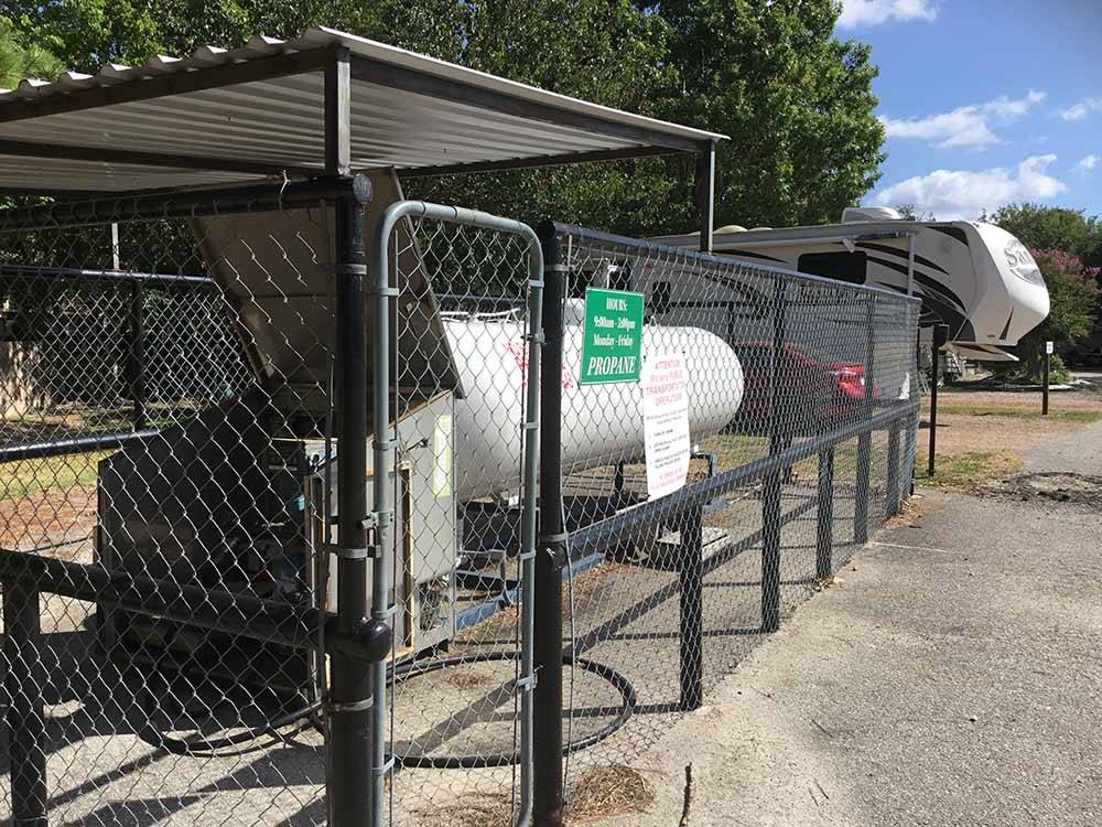 Large propane tank surrounded by chain linked fence at WOODLAND LAKES RV PARK