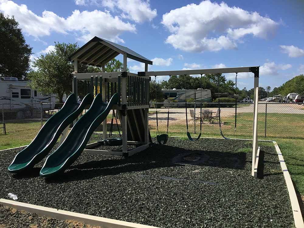 Swing set attached to play structure with slide at WOODLAND LAKES RV PARK
