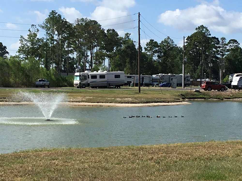 Pond with fountain and RVs on the banks at WOODLAND LAKES RV PARK