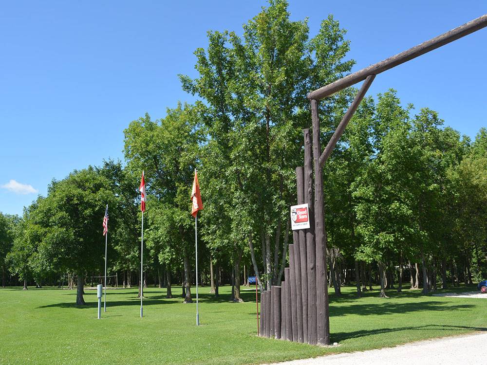 Logs form entrance gate along with three flag poles at MILLER'S CAMPING RESORT