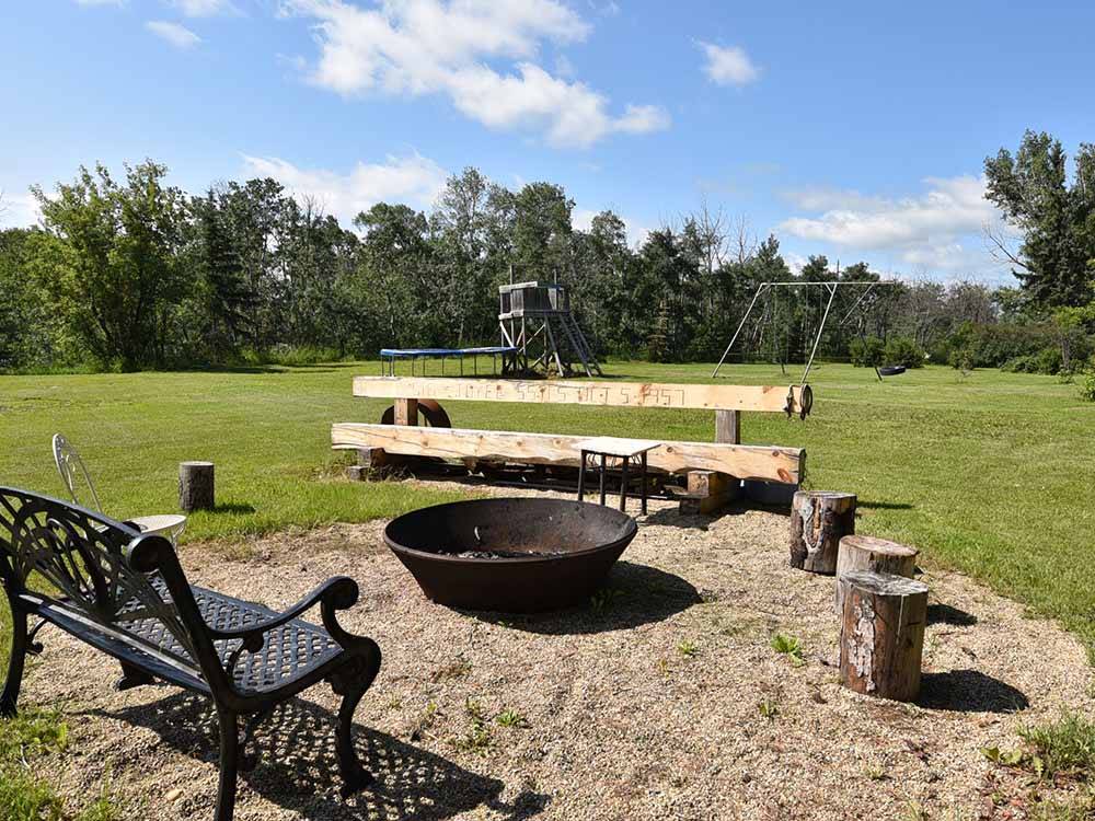 A fire pit with a playground in the background at COUNTRY ROADS RV PARK