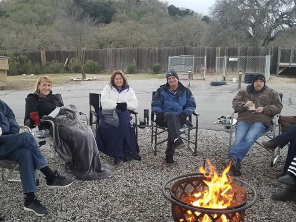 People sitting in a circle around a camp fire ring at PASO ROBLES RV RANCH
