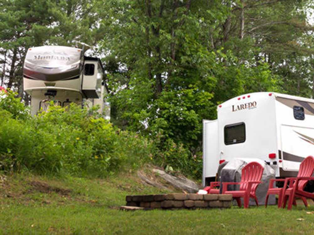 A fire pit with two red chairs next to an RV site at SUGAR RIDGE RV VILLAGE & CAMPGROUND