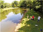 View larger image of Adults and kids relax on banks of a waterway at MOUNTAIN VISTA CAMPGROUND image #11