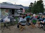 A group of people watching a movie on the side of a motorhome at MANOR RV PARK - thumbnail