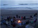 Group of people gathering for bonfire at beach at SEA & SAND RV PARK - thumbnail