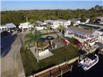 Aerial view of mobile home park with palm trees and American flag at UPRIVER RV RESORT - thumbnail