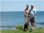 View larger image of A couple walking their dogs next to the ocean at LIBBYS OCEANSIDE CAMP image #2