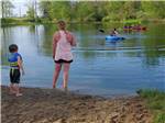 A lady and little boy standing by the lake watching people in kayaks at INDIAN CREEK CAMP & CONFERENCE CENTER - thumbnail