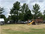 View larger image of Green field with play structure with yellow slide at SUMMER BREEZE CAMPGROUND  RV PARK image #9