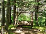A swinging bench under trees at KALKASKA RV PARK & CAMPGROUND - thumbnail