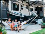 A family sitting on a hammock next to their trailer at SAN DIEGO RV RESORT - thumbnail