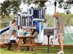 A family sits at a picnic table at Bayberry RV Park - thumbnail