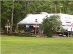 A travel trailer next to the grass at WHISPERING PINES CAMPING ESTATES - thumbnail