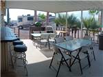 View larger image of Tables and chairs under the patio awning at TRADEWINDS RV PARK image #5