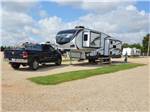 View larger image of Fifth wheel and pickup truck in campsite at TWIN PINE RV PARK image #6