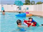View larger image of A father helps his son swim on a floating device at SOUTHERN OAKS RV RESORT image #3
