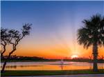View larger image of Sunrise over water with trees in foreground at SOUTHERN OAKS RV RESORT image #5