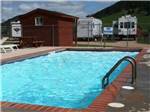 View larger image of The pool with camp sites behind it at NO NAME CITY LUXURY CABINS  RV PARK image #1