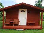 Red cabin with porch, white door and chairs at NO NAME CITY LUXURY CABINS & RV PARK - thumbnail