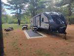 RV at site with picnic table in trees - thumbnail