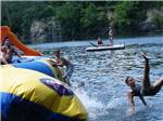 Group of kids playing on yellow and blue inflatable on large lake at HIDDEN PARADISE CAMPGROUND - thumbnail