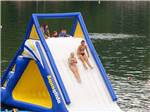 People sliding down large inflatable slide into the water at HIDDEN PARADISE CAMPGROUND - thumbnail