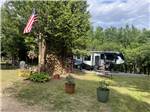 A shady RV site, firewood and flag - thumbnail