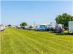 Two rows of motorhomes and trailers parked on grassy sites at SANDBAR RV RESORT - thumbnail