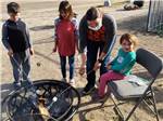 View larger image of Kids roasting marshmallows over a fire at VERDE RIVER RV RESORT  COTTAGES image #2