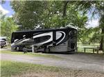 A motorhome on an RV site by the water at WENDY OAKS RV RESORT - thumbnail