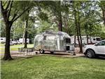A small airstream trailer in a paved site at WENDY OAKS RV RESORT - thumbnail