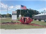 An old stagecoach with scarecrows in it next to a flag - thumbnail