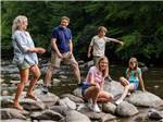 A family standing on rocks in a creek at Pigeon Forge Department Of Tourism - thumbnail