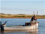 A man with two longs sticks in a boat at PEI PROVINCIAL PARKS - thumbnail