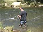 A man fishing while standing in the river at FRANDY PARK CAMPGROUND - thumbnail