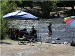 People sitting in the water under an EZ Up at FRANDY PARK CAMPGROUND - thumbnail