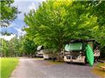 A green kayak leans against a Class A Motorhome parked in a well-shaded back-in RV space at TRIPLE CREEK CAMPGROUND - thumbnail