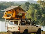 View larger image of A truck with a tent on top by a lake at FARM COUNTRY CAMPGROUND image #10