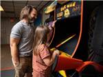 A father and daughter playing an arcade game at Natalbany Creek Campground & RV Park - thumbnail